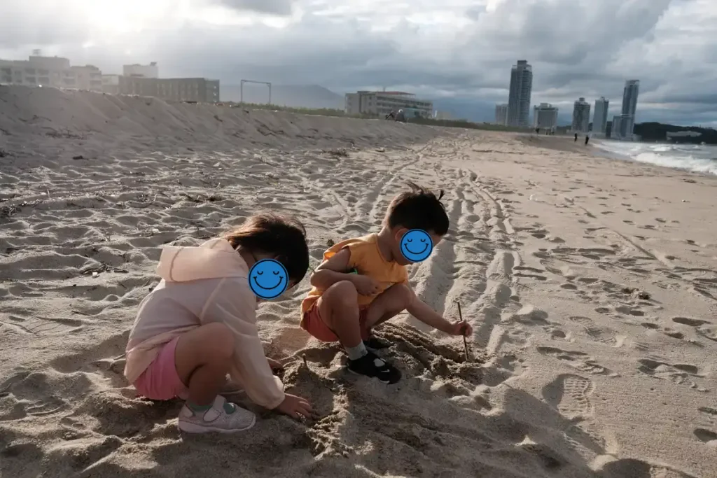 넓은 해변에서 모래놀이에 열중한 아이들